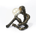 Bronze Industrial Pipe Robot Table Lamp with Clear Globe Bulb - Front View | Playful Steampunk Sculpture Lighting for Modern Home & Office Decor